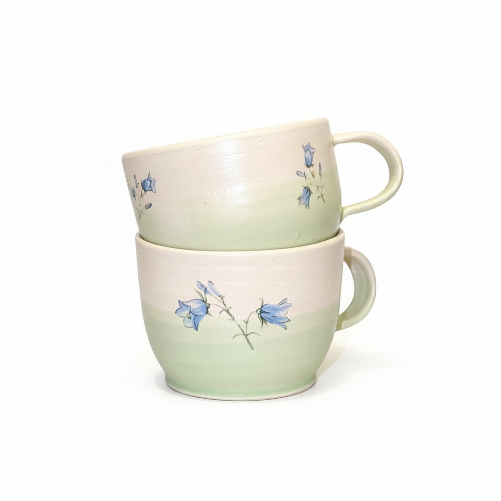 Two ceramic mugs with floral design on a white background