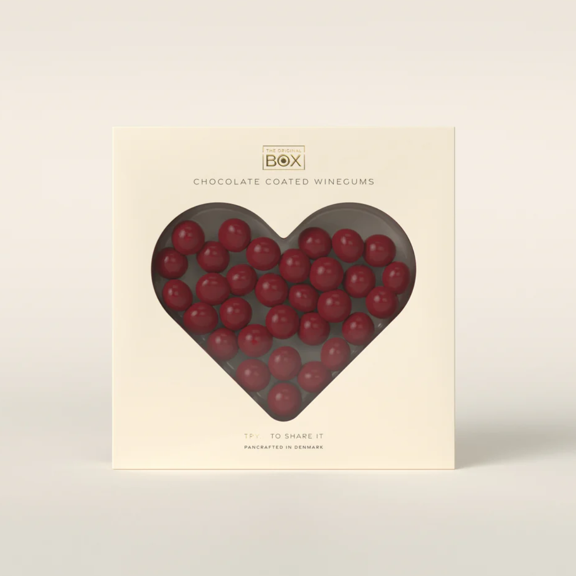 Box of chocolate-coated wine gums with a heart-shaped window on a beige background