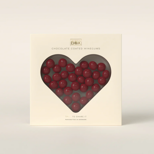 Box of chocolate-coated wine gums with a heart-shaped window on a beige background