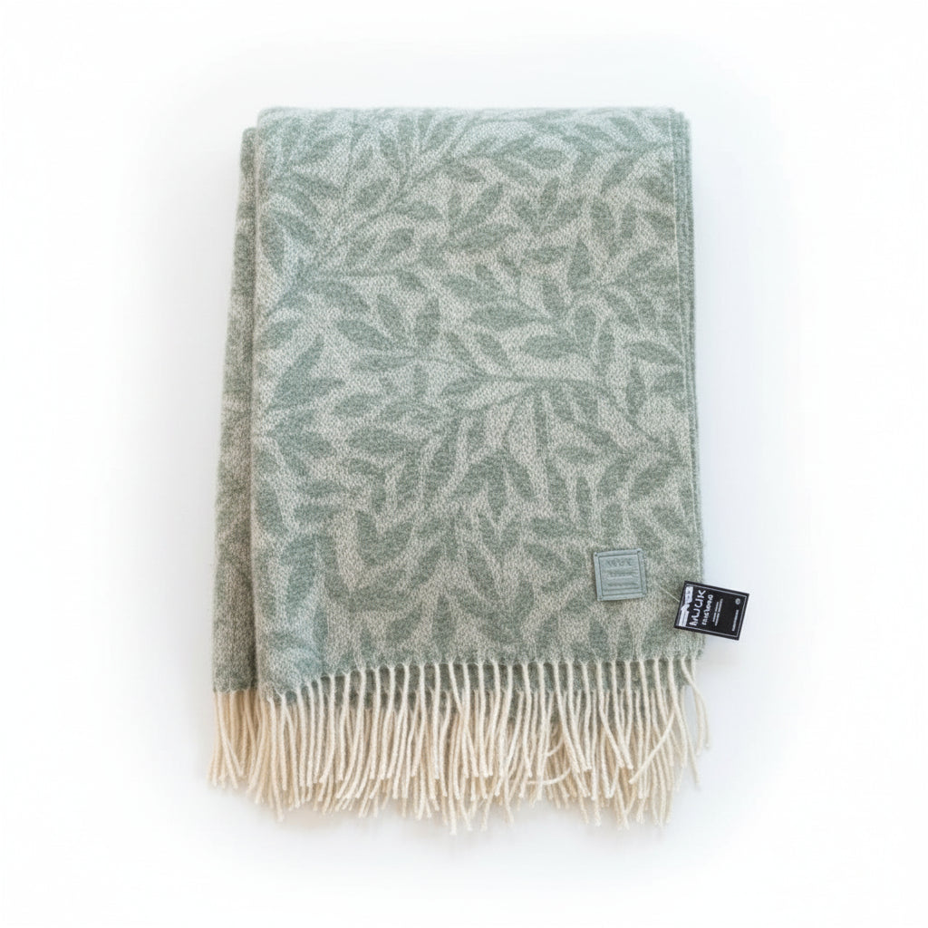 Green patterned throw blanket with a label on a beige surface